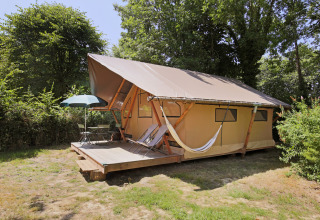 Safari tent Trappeur Tent at Huttopia Baie du Mont St Michel in France, featuring a deck, hammock, and chairs.