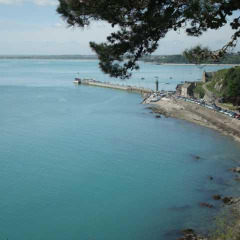 Vista del tranquilo mar azul y la costa en Huttopia Baie du Mont St Michel en Bretaña, Francia.