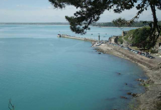 View of the calm blue sea and coastline at Huttopia Baie du Mont St Michel holiday park in Brittany, France.