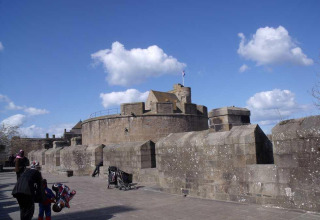 Et billede af en stenhøj borg under blå himmel ved Huttopia Baie du Mont St Michel, Bretagne, Frankrig.
