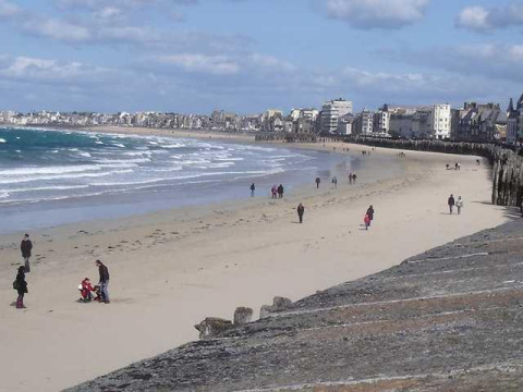Vista sulla spiaggia di Huttopia Baie du Mont St Michel con persone e edifici in Bretagna, Francia.