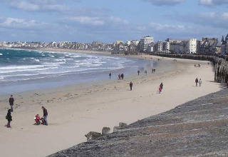 Strandblick am Huttopia Baie du Mont St Michel mit Spaziergängern und Gebäuden in der Bretagne, Frankreich.