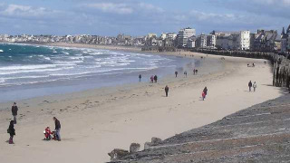 Vista de la playa en Huttopia Baie du Mont St Michel con personas y edificios en Bretaña, Francia.