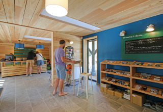 Receptionen hos Huttopia Baie du Mont St Michel i Bretagne, Frankrig, med gæster og informationsbøger.