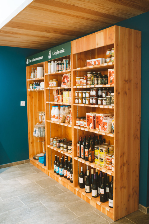 Wooden shelves with local grocery items and wine at Huttopia Baie du Mont St Michel holiday park in Brittany.