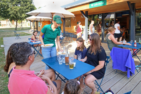 Udendørs restaurant på Huttopia Baie du Mont St Michel feriested, gæster bliver serveret mad.