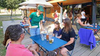 Comedor al aire libre en Huttopia Baie du Mont St Michel, Bretaña, Francia, camarera sirviendo comida.