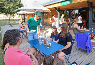Udendørs restaurant på Huttopia Baie du Mont St Michel feriested, gæster bliver serveret mad.