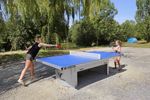 Madre e hija juegan al tenis de mesa al aire libre en Huttopia Baie du Mont St Michel en Bretaña.