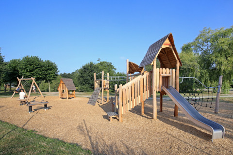 Parque infantil con columpios, tobogán y estructuras de madera en Huttopia Baie du Mont St Michel, Bretaña, Francia.