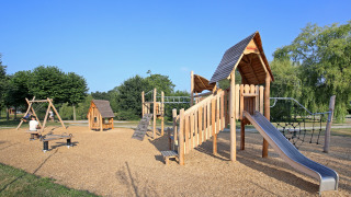 Parque infantil con columpios, tobogán y estructuras de madera en Huttopia Baie du Mont St Michel, Bretaña, Francia.