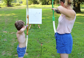 Un adulto e un bambino praticano tiro con l’arco su un prato in un villaggio vacanze in Bretagna, Francia.