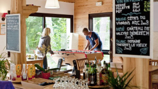 Innenaufnahme von Huttopia Rambouillet mit Gästen, die Tischfußball in einem gemütlichen Café spielen.