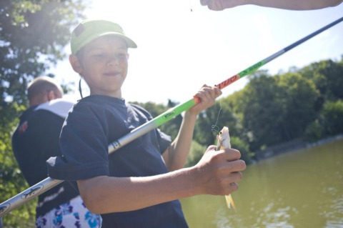Niño pescando junto a un lago en un día soleado en Huttopia Rambouillet, Île de France, Francia.