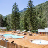 Outdoor swimming pool with sun loungers at Huttopia Bozel en Vanoise, nestled among green forested mountains.