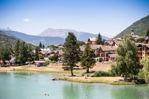 Vista panorámica de Bozel con cabañas junto al lago y montañas en Auvernia-Ródano-Alpes, Francia, en un día soleado.
