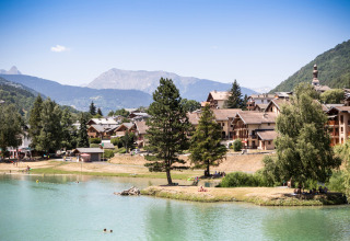 Blick auf Bozel mit Chalets, See und Bergen in der Region Auvergne-Rhône-Alpes, Frankreich, an einem klaren Tag.