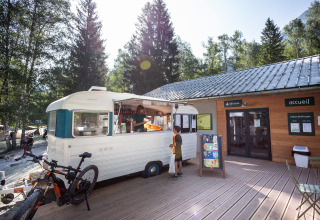 Dreng bestiller fra en madvogn foran en træbygning på ferieparken Huttopia Bozel en Vanoise i Frankrig.
