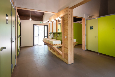 Baño moderno y espacioso en Huttopia Bozel en Vanoise con puertas verdes y detalles en madera.