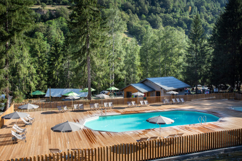 Piscina al aire libre con tumbonas y sombrillas en Huttopia Bozel en Vanoise, Auvergne-Rhône-Alpes, Francia.