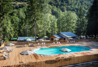 Piscina al aire libre con tumbonas y sombrillas en Huttopia Bozel en Vanoise, Auvergne-Rhône-Alpes, Francia.