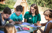 Bambini che disegnano con un’animatrice all’aperto all’Huttopia Bozel en Vanoise in Francia.