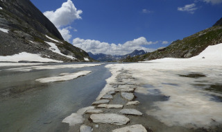 Camino de piedras atraviesa nieve y agua en las montañas cerca de Bozel, Auvergne-Rhône-Alpes, Francia.