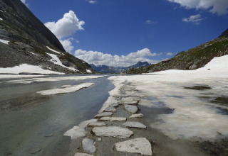 Chemin de pierres traversant neige et eau à proximité de Bozel, Auvergne-Rhône-Alpes, dans les Alpes.