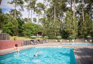 Udendørs swimmingpool ved Huttopia Landes Sud feriepark omgivet af fyrretræer i Nouvelle-Aquitaine, Frankrig.