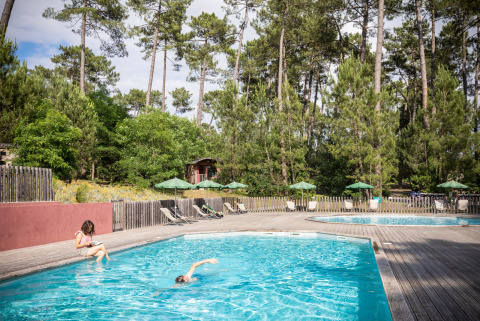 Outdoor swimming pool at Huttopia Landes Sud holiday park, surrounded by pine trees in Nouvelle-Aquitaine, France.