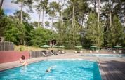Piscina exterior en el parque vacacional Huttopia Landes Sud, rodeada de pinos en Nouvelle-Aquitaine, Francia.