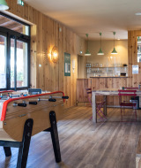 Gemütlicher Aufenthaltsraum im Huttopia Landes Sud mit Kicker, Holzdekor und einer kleinen Bar.