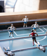 Mesa de futbolín con jugadores rojos y blancos en un parque vacacional con alojamientos glamping.