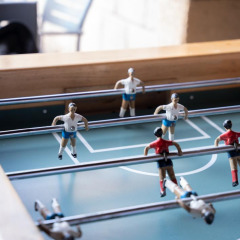 Mesa de futbolín con jugadores rojos y blancos en un parque vacacional con alojamientos glamping.
