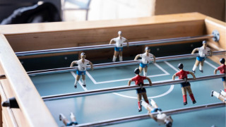 Mesa de futbolín con jugadores rojos y blancos en un parque vacacional con alojamientos glamping.