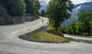 Ciclista en una carretera de montaña sinuosa cerca de Castellane, Hauts-de-France, Francia, en un día brumoso.