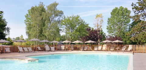 Piscina al aire libre con tumbonas y sombrillas en Huttopia Etang de Fouché, Bourgogne, Francia.