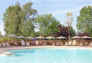 Outdoor swimming pool with sun loungers and umbrellas at Huttopia Etang de Fouché in Bourgogne, France.