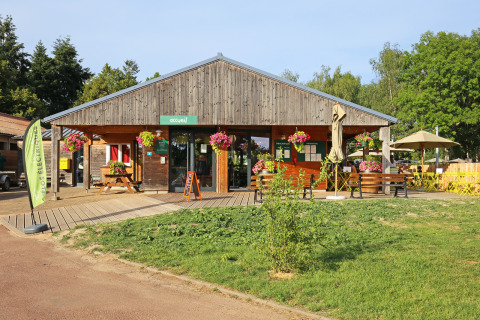 Edificio principal de madera con flores en Huttopia Etang de Fouché, parque vacacional en Borgoña, Francia