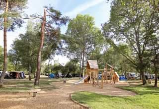 Legeplads med rutchebane og klatrestativ blandt telte og træer i ferieparken Huttopia Etang de Fouché, Bourgogne.