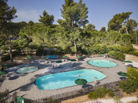 Zona de piscinas en el parque vacacional Huttopia Fontvieille, rodeado de pinos en Provenza-Alpes-Costa Azul, Francia.