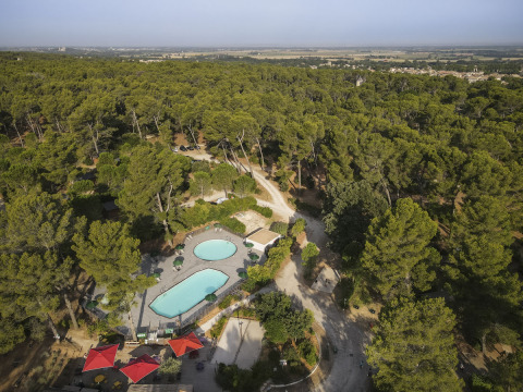 Vista aérea del parque vacacional Huttopia Fontvieille en Provenza-Alpes-Costa Azul, Francia, rodeado de bosque.