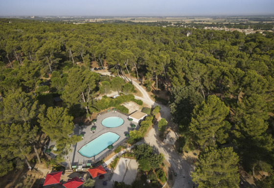 Luchtfoto van vakantiepark Huttopia Fontvieille in Provence-Alpes-Côte d’Azur, Frankrijk, omgeven door bos.
