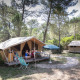 Safari-bungalowtelt i skoven ved Huttopia Fontvieille i Frankrig med folk, der slapper af udenfor.