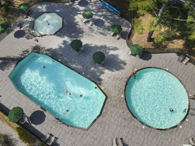 Luchtfoto van zwembaden en ontspanningsruimte bij Huttopia Fontvieille vakantiepark in Provence-Alpes-Côte d’Azur, Frankrijk.
