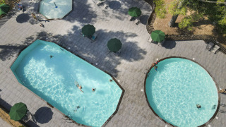 Vista aérea de piscinas y zona de relax en el parque vacacional Huttopia Fontvieille en Provenza-Alpes-Costa Azul, Francia.