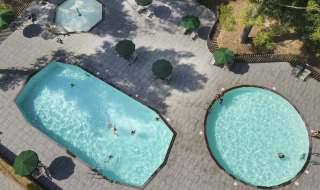 Vista aérea de piscinas y zona de relax en el parque vacacional Huttopia Fontvieille en Provenza-Alpes-Costa Azul, Francia.