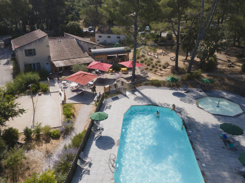 Vista aérea de la zona de piscina y terraza del parque vacacional Huttopia Fontvieille en Provenza.