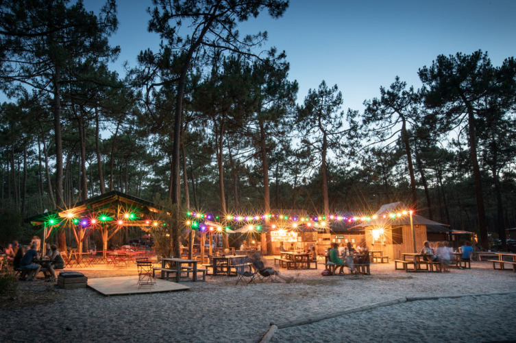 Avondsfeer met lichtslingers en banken bij Huttopia Lac de Carcans vakantiepark in Nouvelle-Aquitaine, Frankrijk.