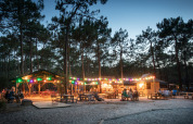 Atmosfera serale con luci a catena e tavoli a Huttopia Lac de Carcans, parco vacanze in Nouvelle-Aquitaine, Francia.